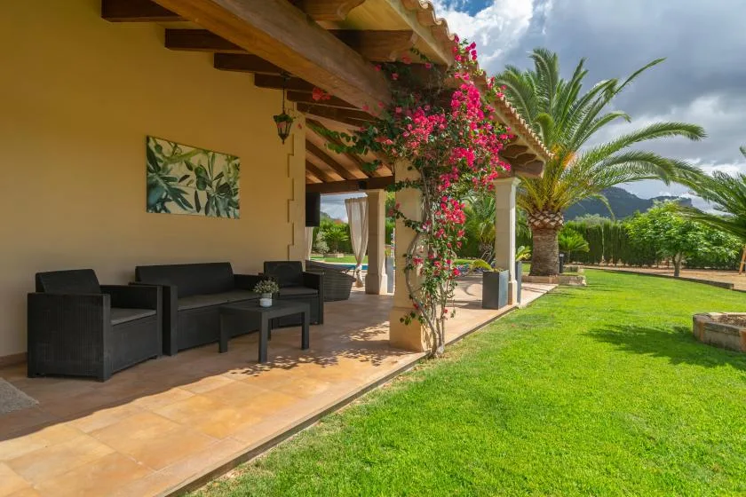 Un patio cubierto con asientos al aire libre da a un césped verde y palmeras.