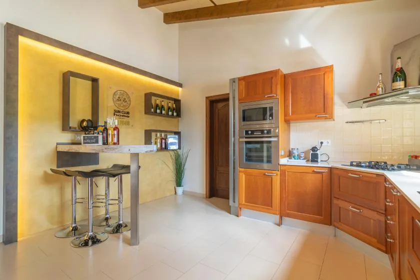 Una cocina con gabinetes de madera, electrodomésticos integrados y una pequeña barra.