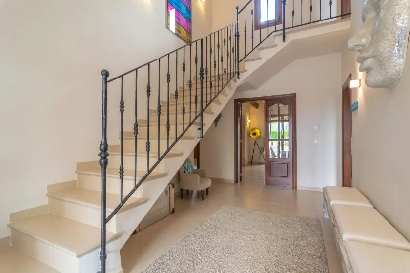 Un recibidor luminoso con una escalera y una alfombra en el suelo.