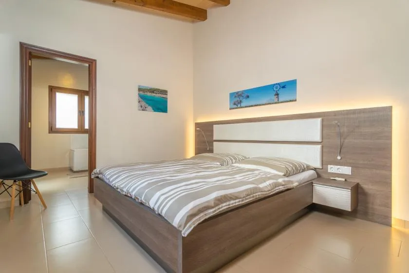 Un dormitorio con una cama doble, un cabecero de pared y dos cuadros.