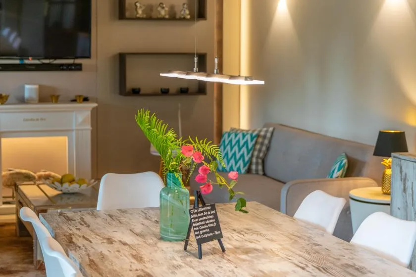 Sala de estar con mesa de comedor, asientos y flores de colores.