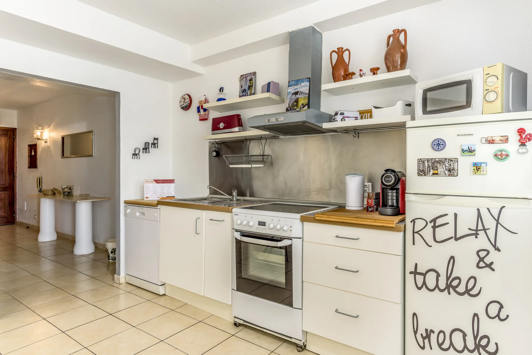 Una cocina luminosa con armarios blancos, una estufa y un refrigerador.