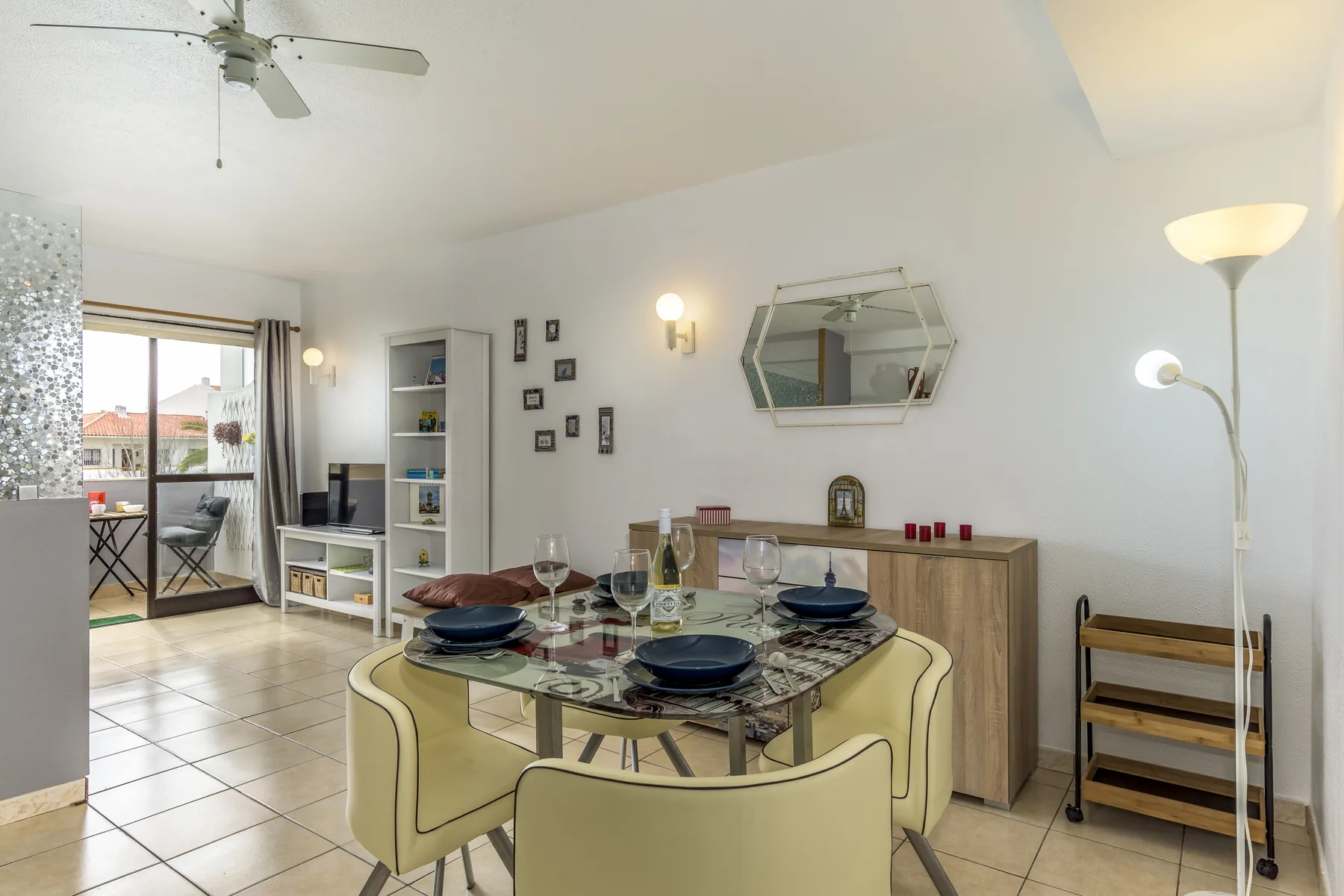 Comedor con mesa de cristal y asientos, junto a una luminosa zona de estar.