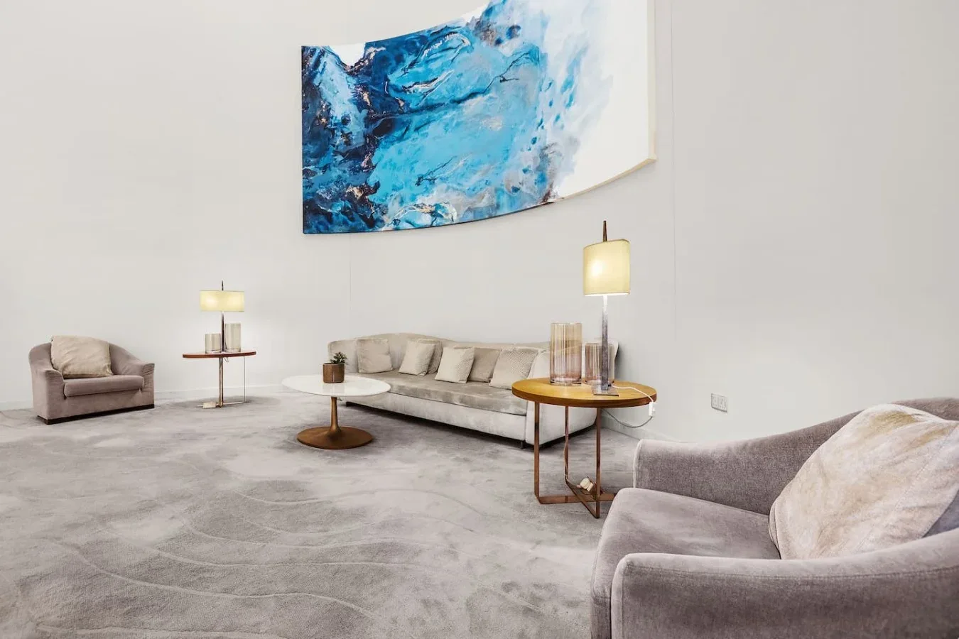 Una sala de estar con asientos, mesas auxiliares y una gran pintura abstracta.