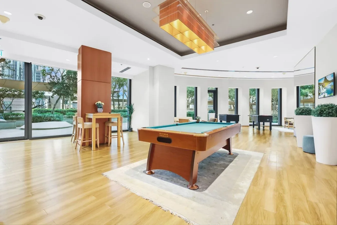 Una luminosa sala de recreación con una mesa de billar y grandes ventanales.