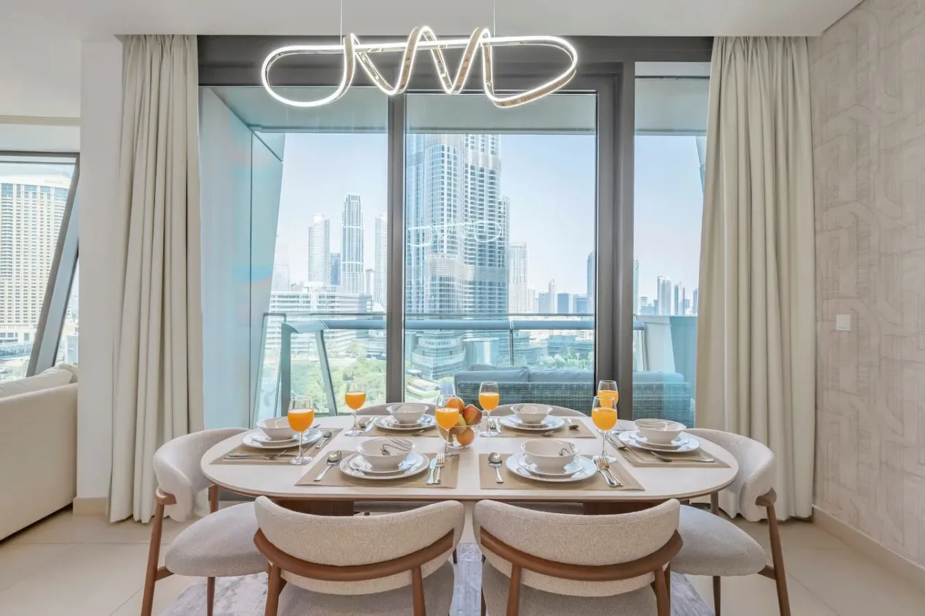A dining area with a set table in front of large windows overlooking city buildings.
