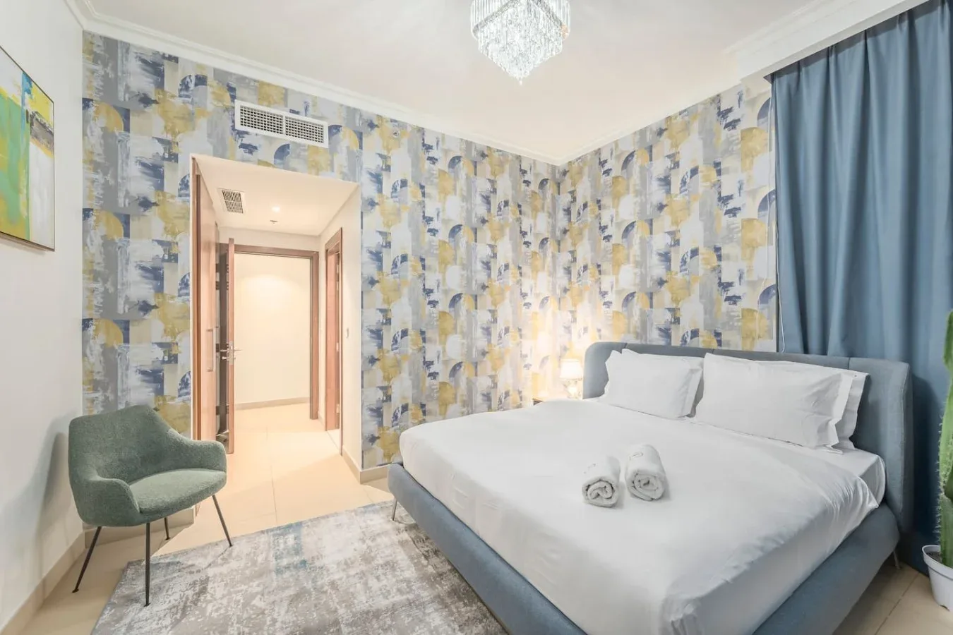 Un dormitorio con una cama grande, paredes estampadas y una cortina azul.