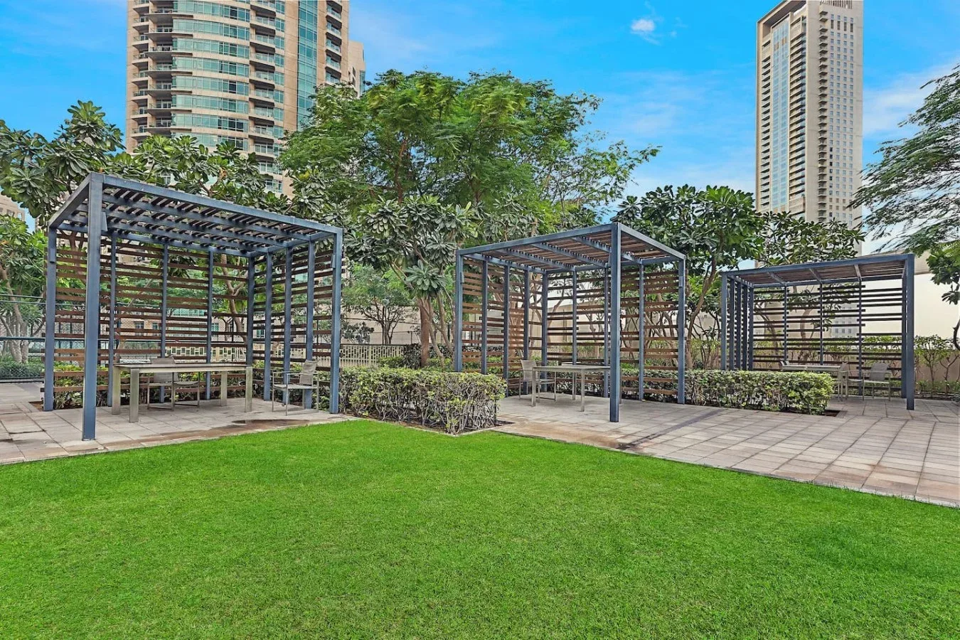 Un patio ajardinado cuenta con césped y estructuras de sombra con asientos.