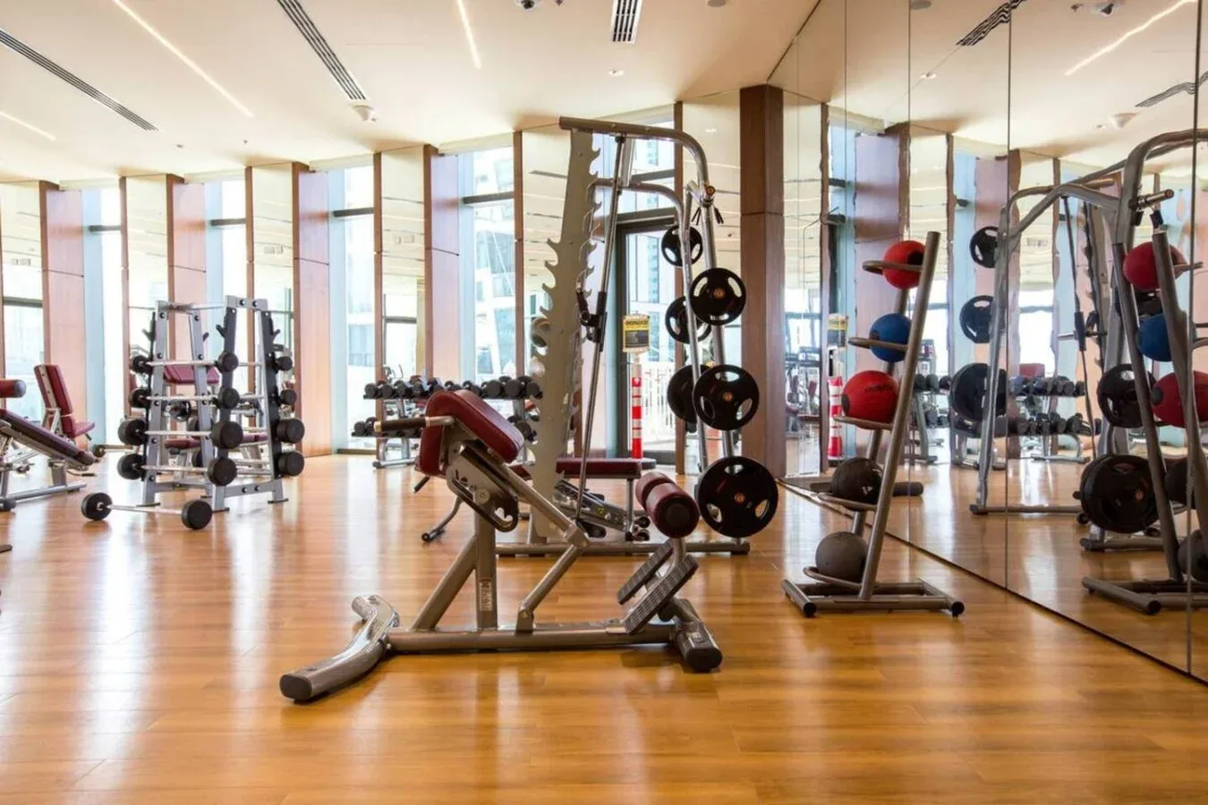 Un gimnasio con máquinas de pesas y equipo de ejercicio junto a paredes con espejos.