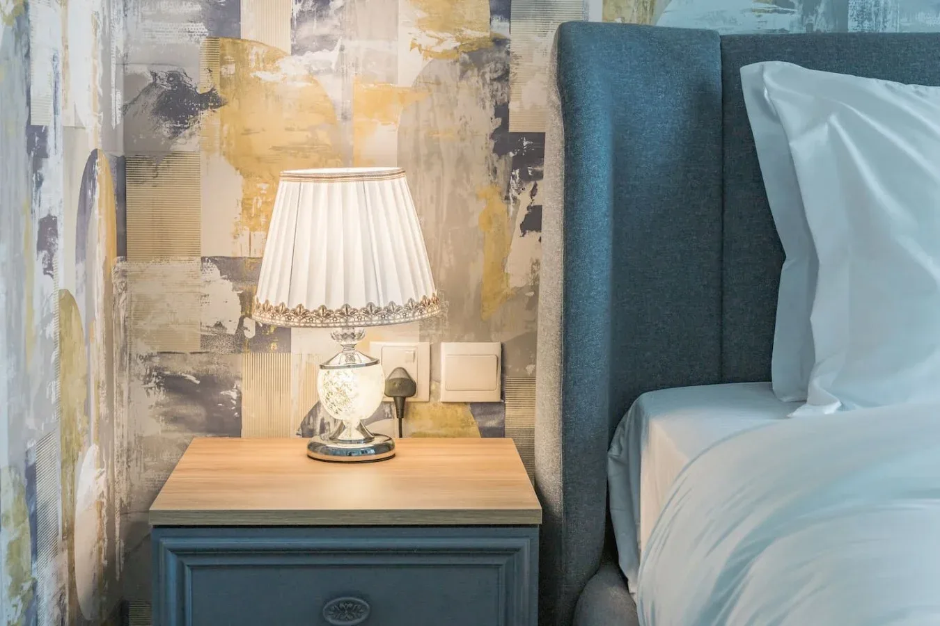 Un dormitorio con una mesita de noche y una lámpara junto a una cama.