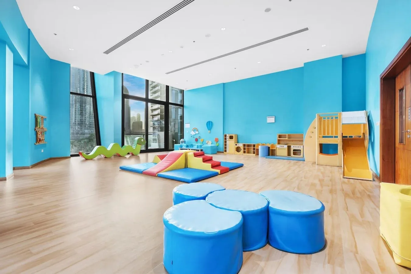 Una colorida sala de juegos interior con juegos acolchados y grandes ventanas.