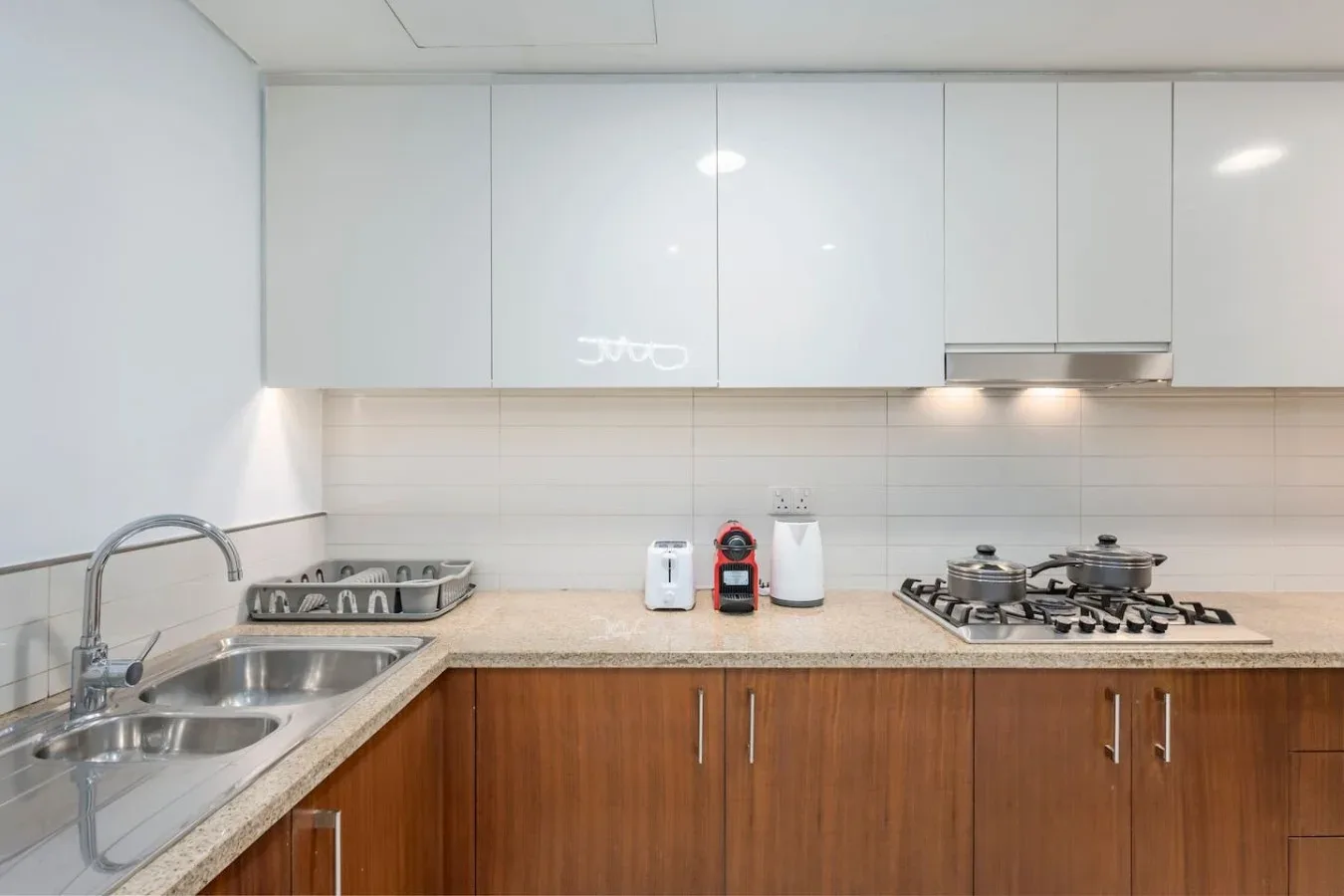 Una cocina con gabinetes inferiores de tono madera, fregadero doble y estufa de gas.