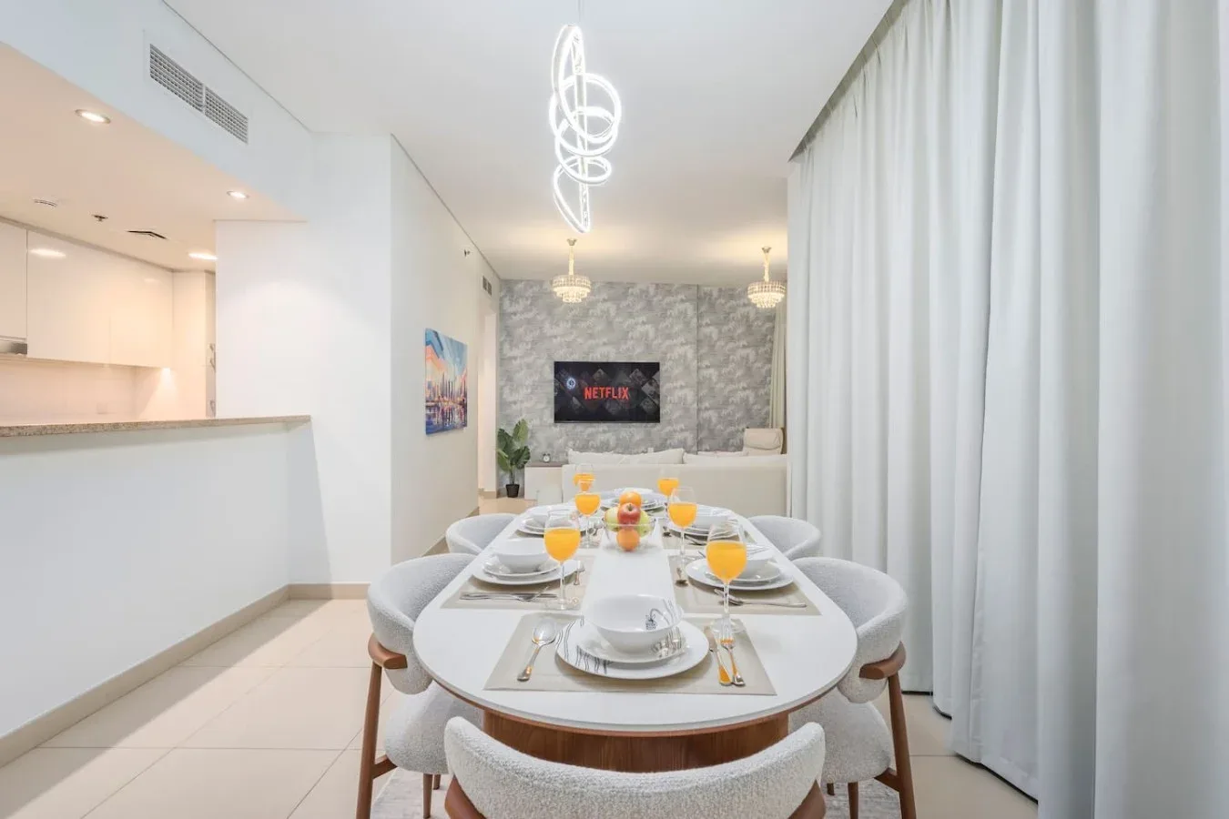 Comedor con una mesa puesta junto a una cocina abierta y luminosa.