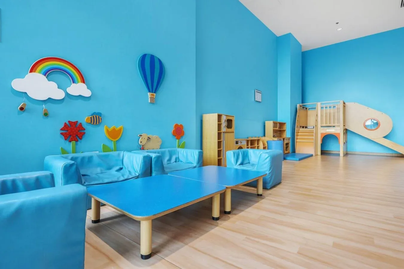 Una colorida sala de juegos interior con asientos acolchados azules y una estructura de madera para trepar.