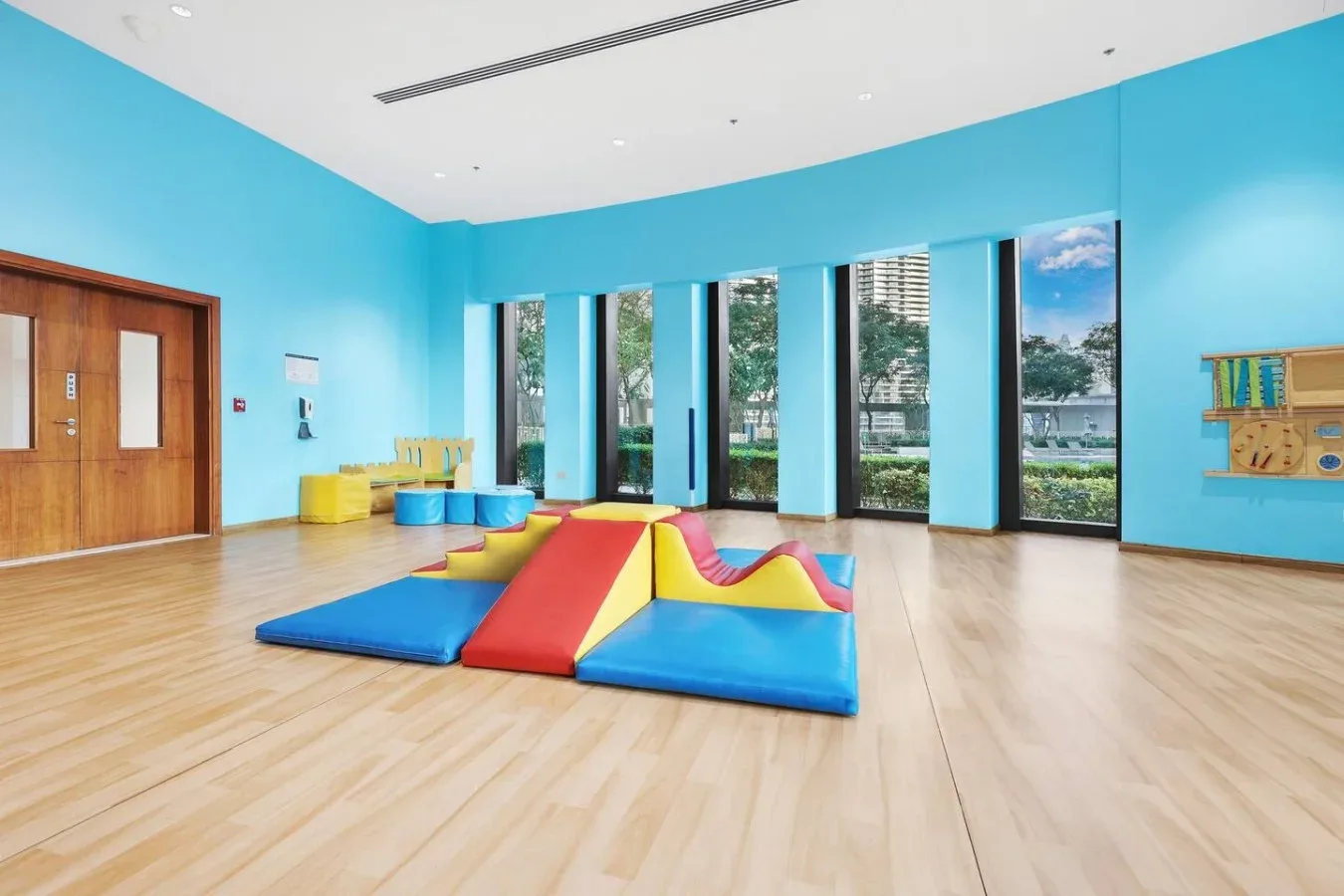 Una sala de juegos luminosa con colchonetas de colores junto a ventanales.