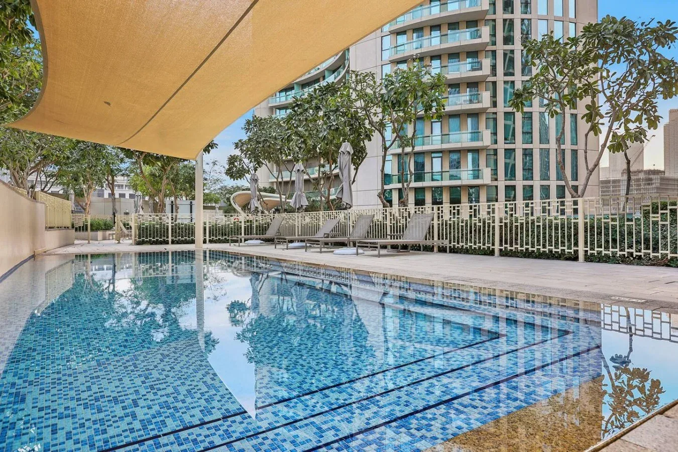 Una piscina al aire libre junto a asientos y edificios modernos.