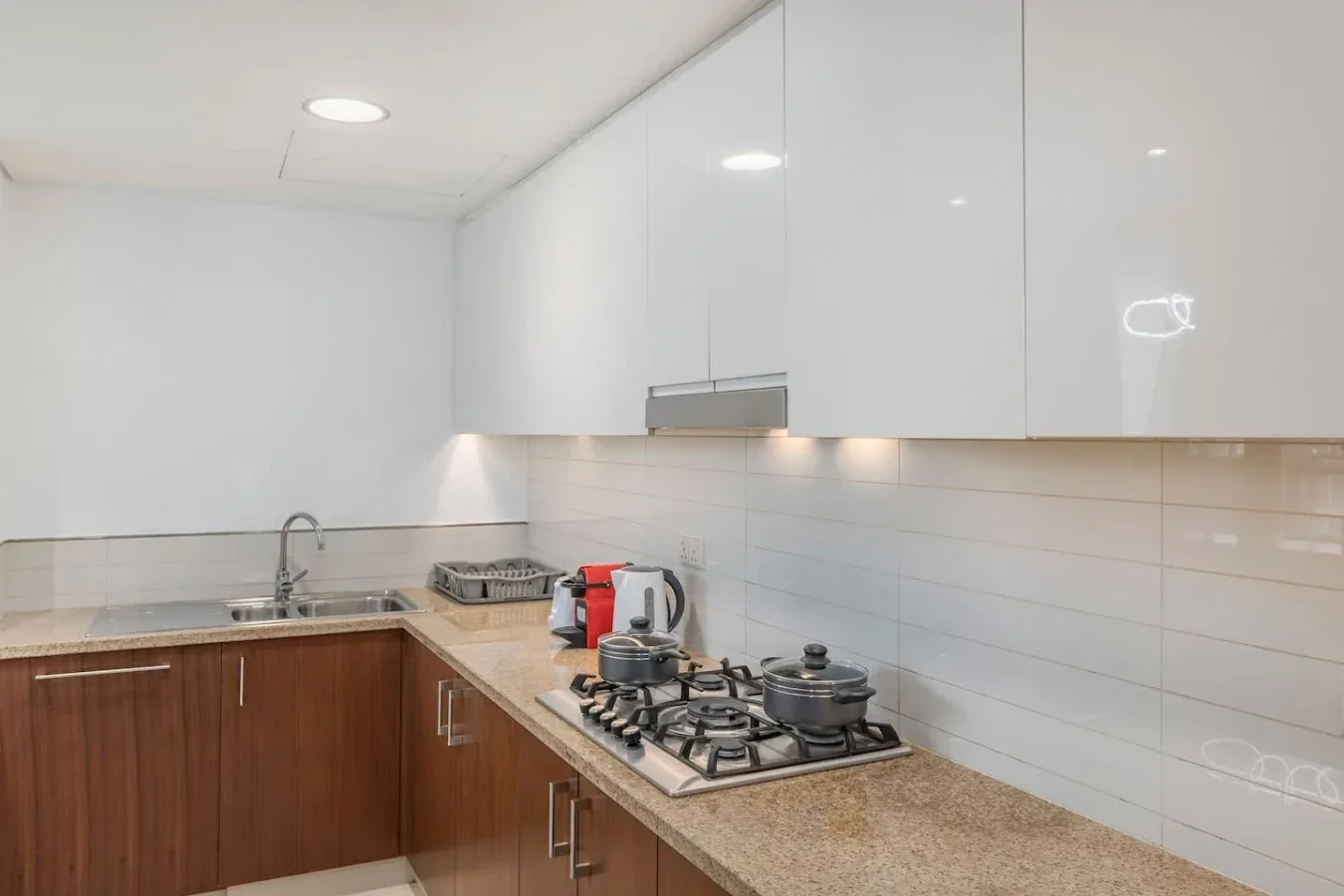 Una cocina moderna con gabinetes blancos, un fregadero y una estufa de gas.