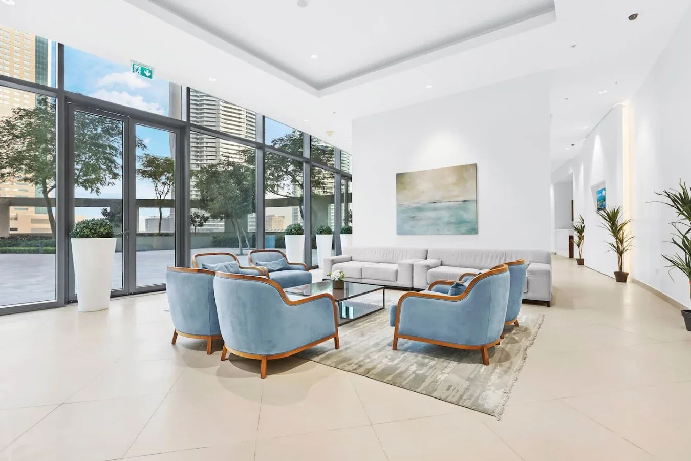 Una sala luminosa con asientos azules alrededor de una mesa de centro de vidrio.