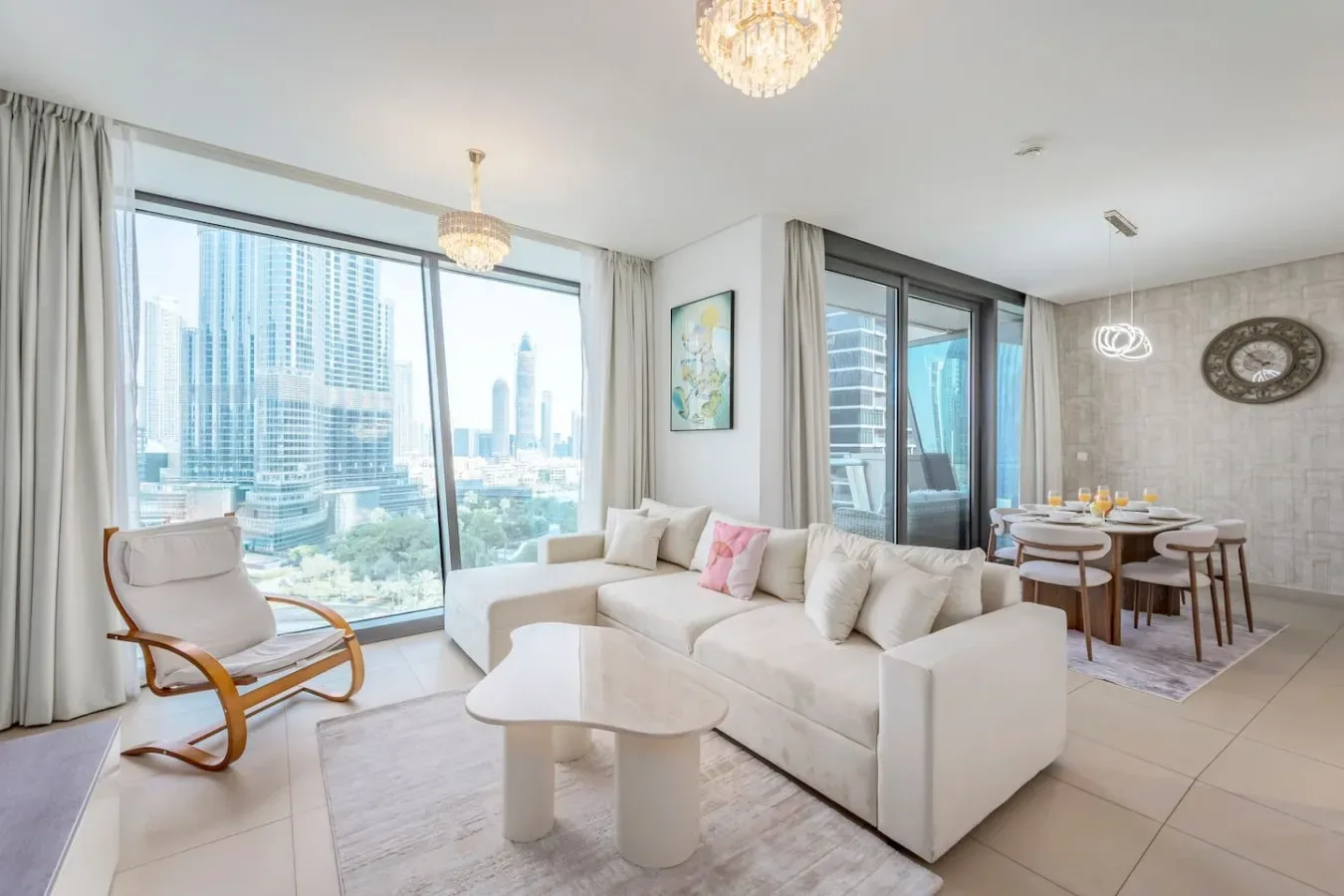 A bright living and dining area with seating beside large windows overlooking the city.