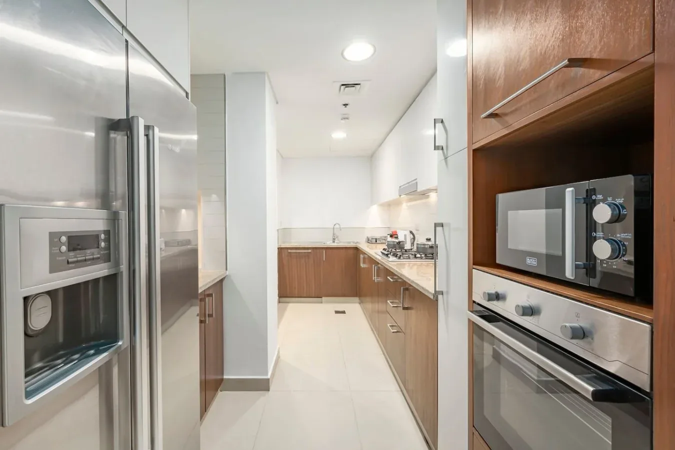 Una cocina alargada con electrodomésticos de acero inoxidable y gabinetes de madera.