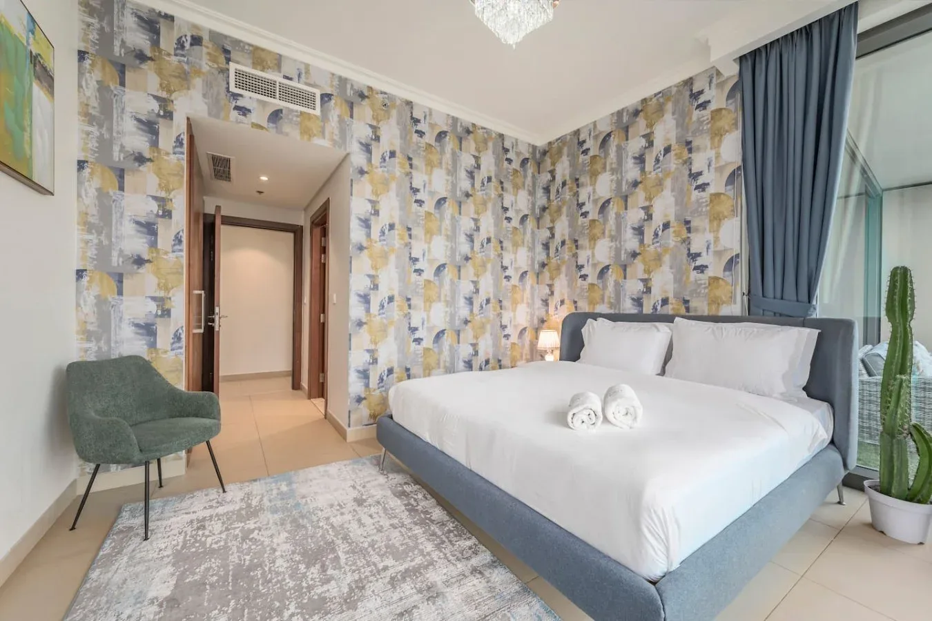 Un dormitorio con una cama grande, papel tapiz estampado y una ventana con cortinas azules.