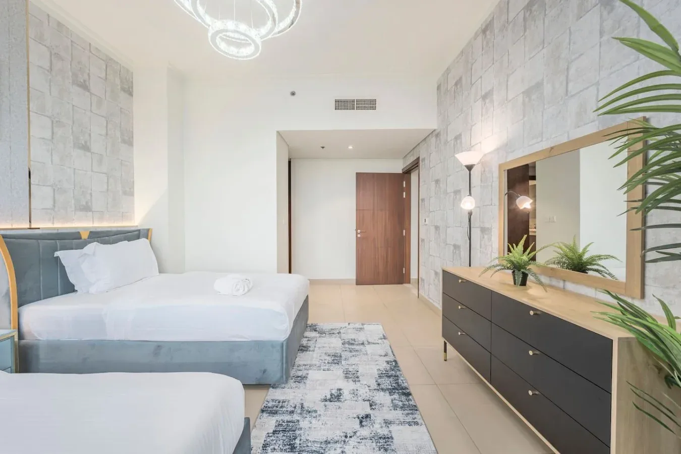 Un dormitorio luminoso con camas, una cómoda larga y un espejo grande.