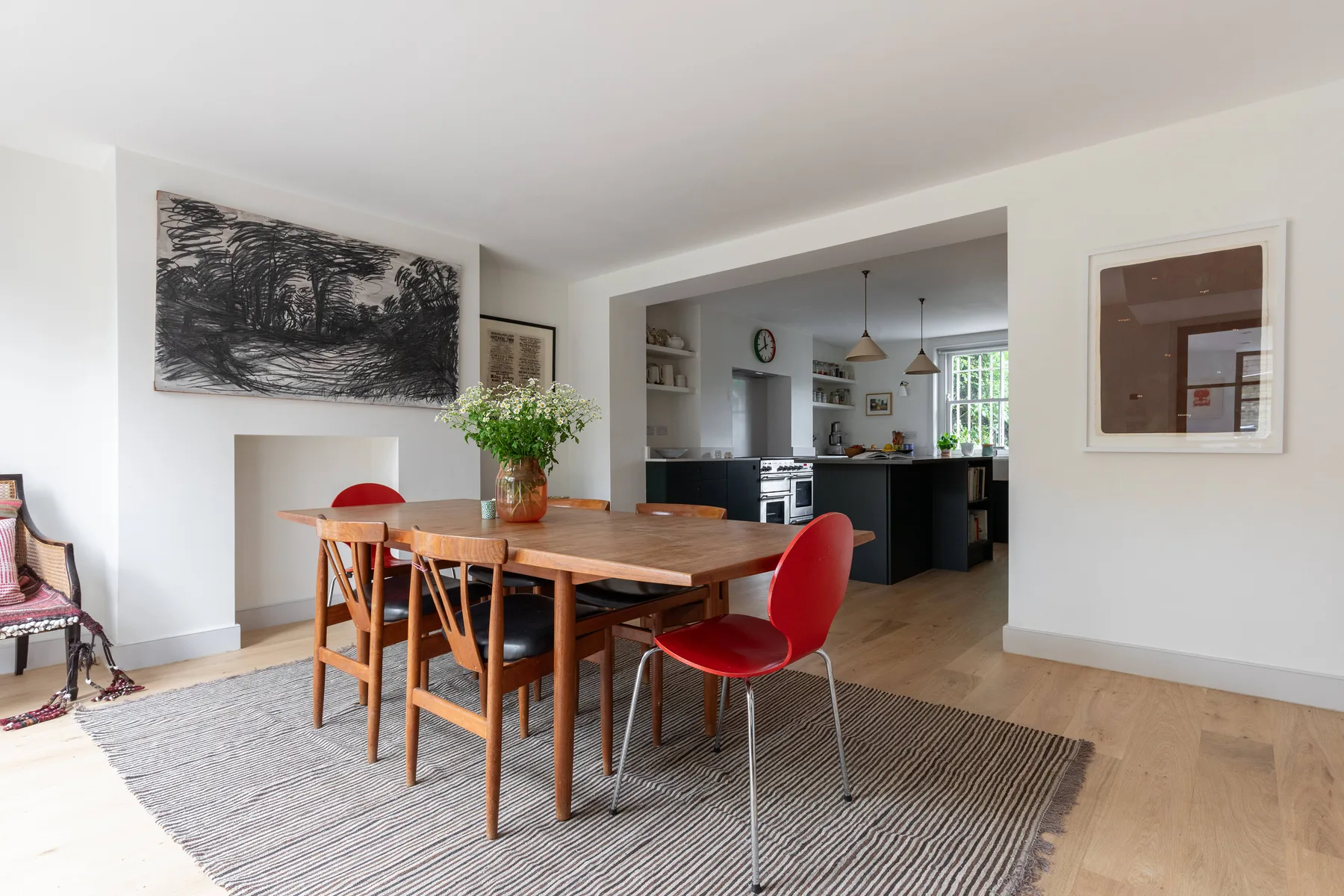 A dining area with a wooden table and chairs beside an open kitchen.
