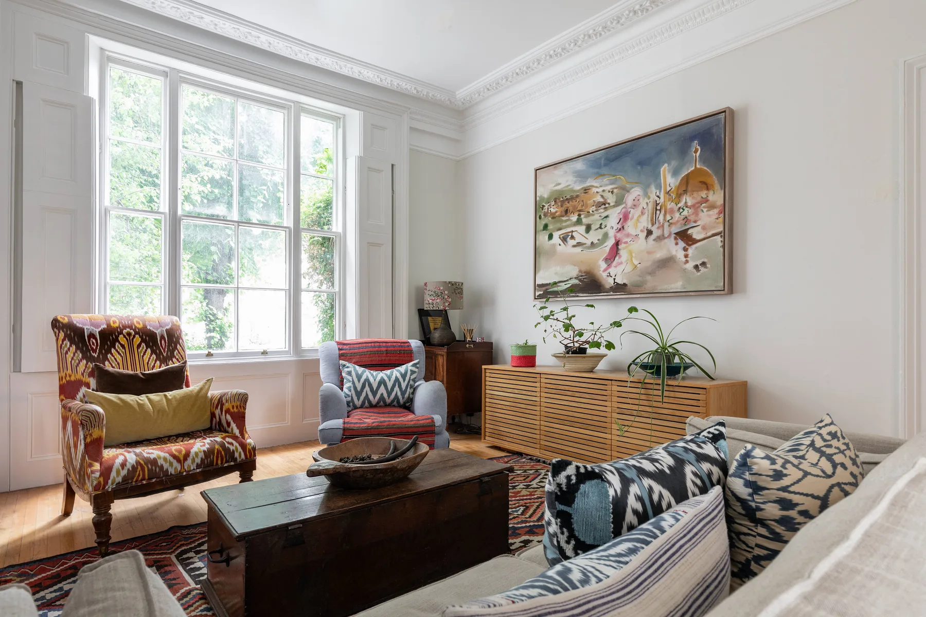 A bright living room with patterned seating and a large window.