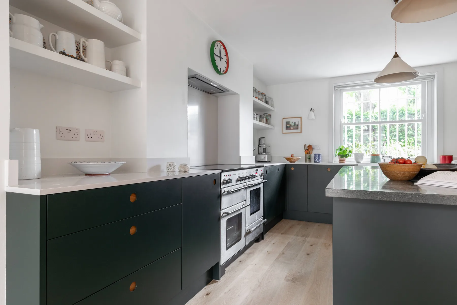 A bright kitchen with dark cabinets, a stove, and a large window.