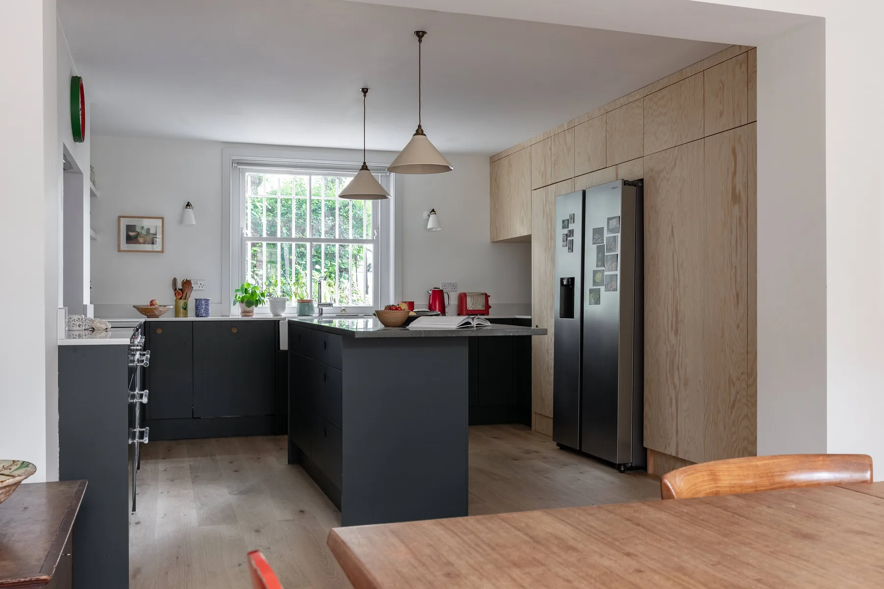A modern kitchen with dark cabinets, a central island, and a large window.