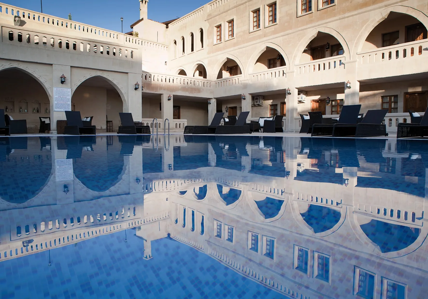 Los arcos de piedra del hotel reflejados en la piscina al aire libre