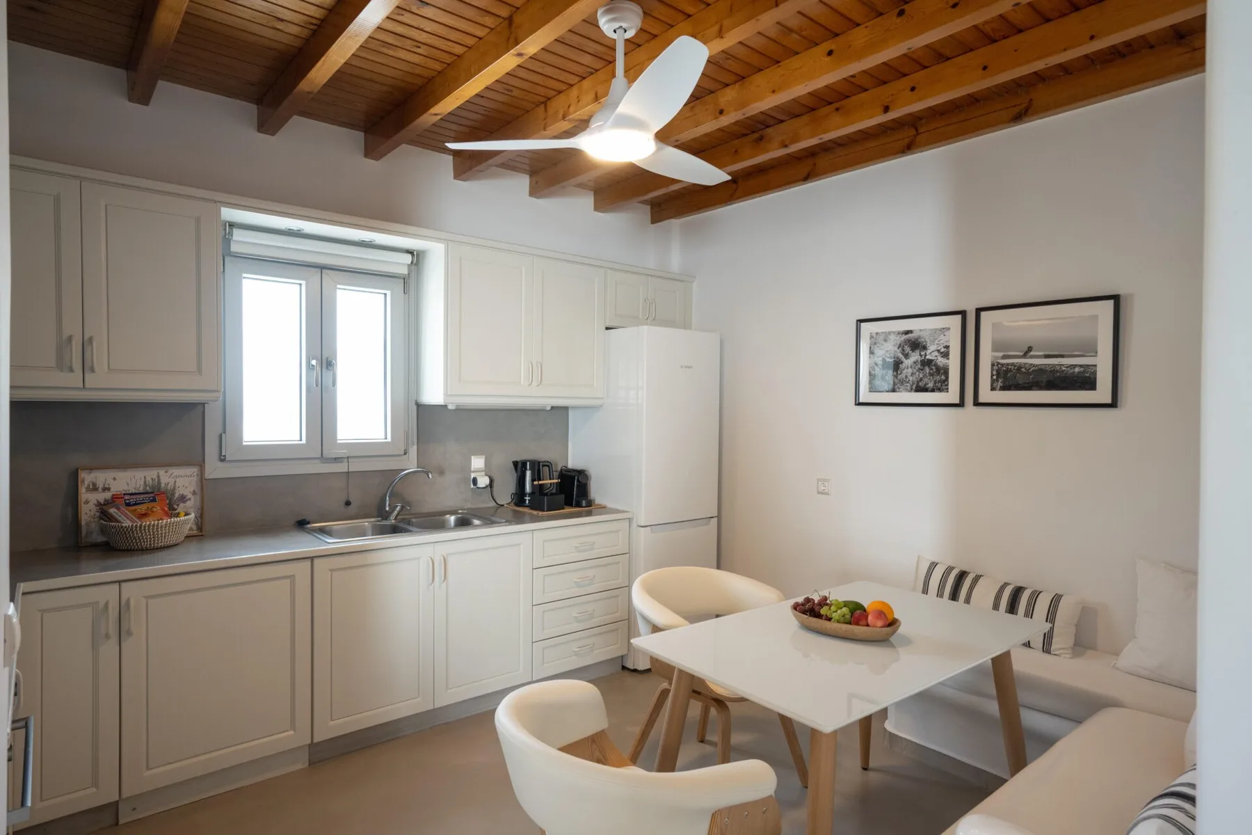 A bright kitchen and dining area with white cabinets and a wooden ceiling.