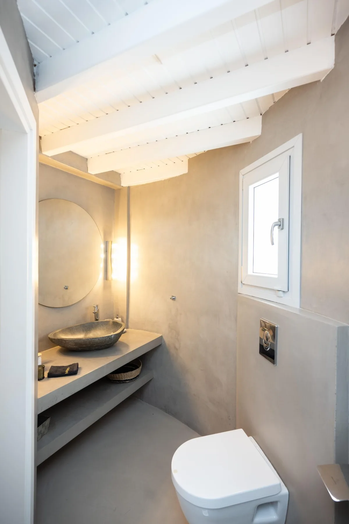 A bathroom with a wall-mounted sink, mirror, and toilet.