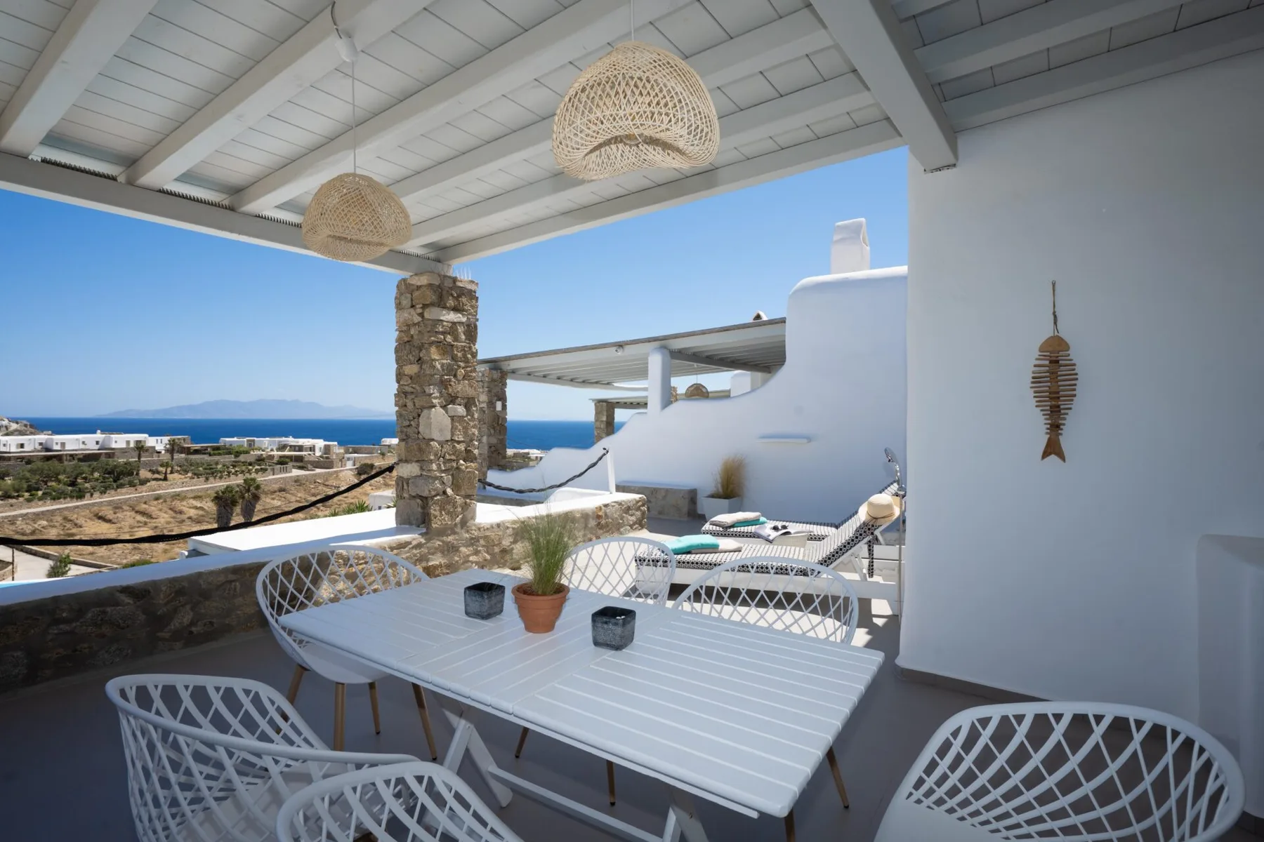 A covered outdoor dining area with a table and views of the sea.