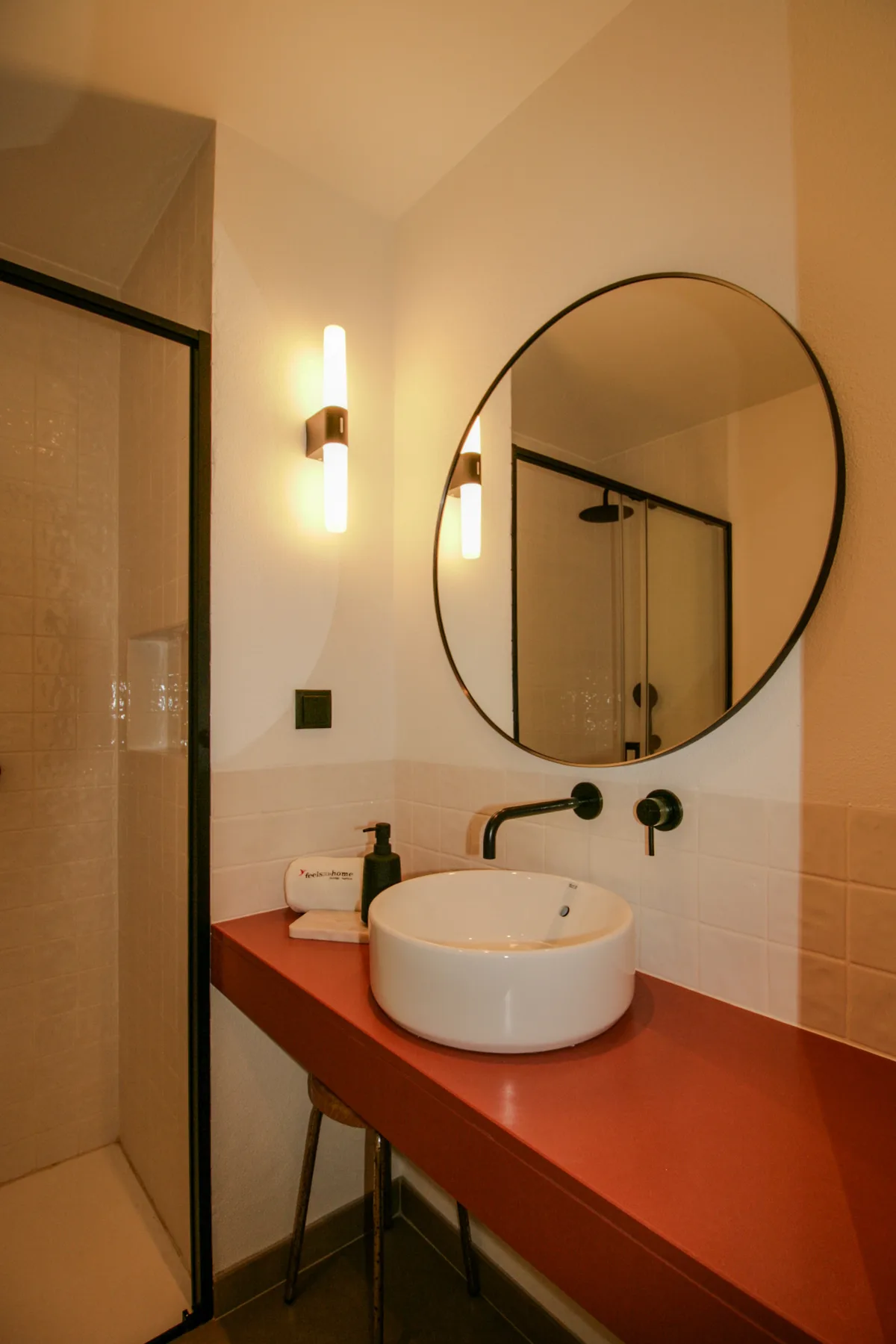 Un baño con un espejo redondo sobre un lavabo blanco.
