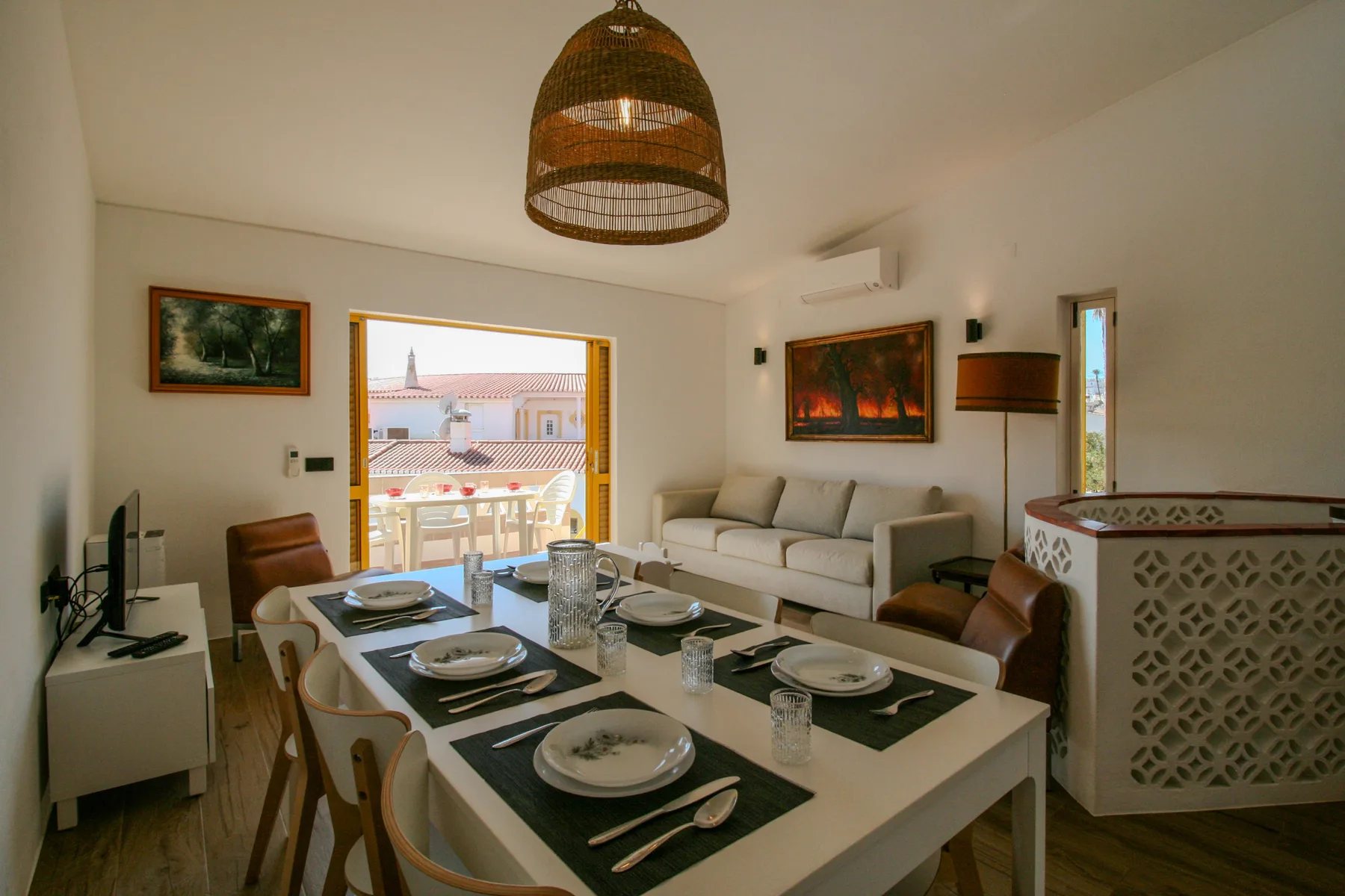 Zona de comedor y estar con la mesa puesta y asientos.