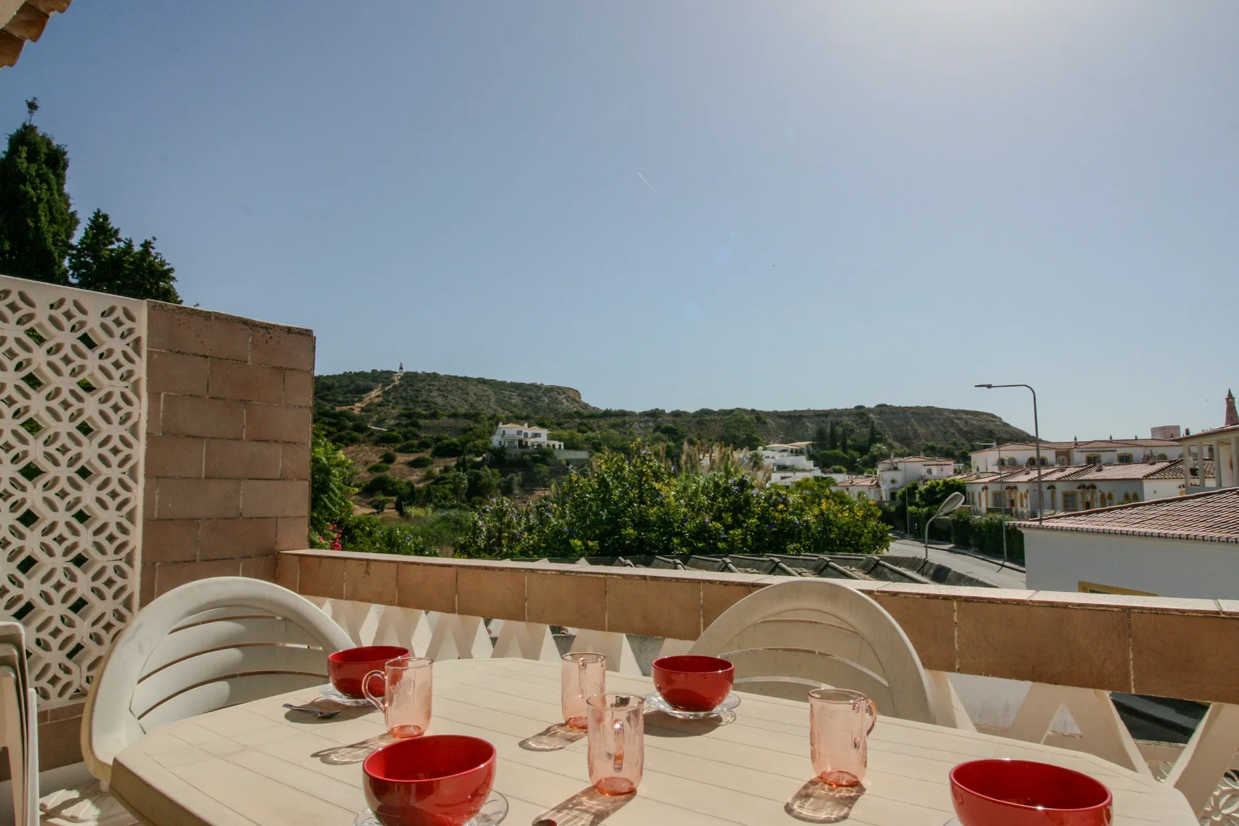 Una zona de comedor en la azotea ofrece vistas a colinas verdes y edificios cercanos.