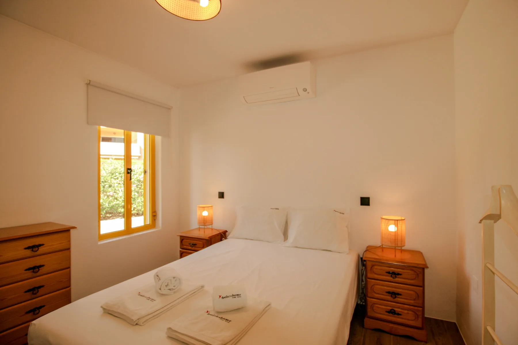Un dormitorio con una cama, mesillas de noche y una ventana.