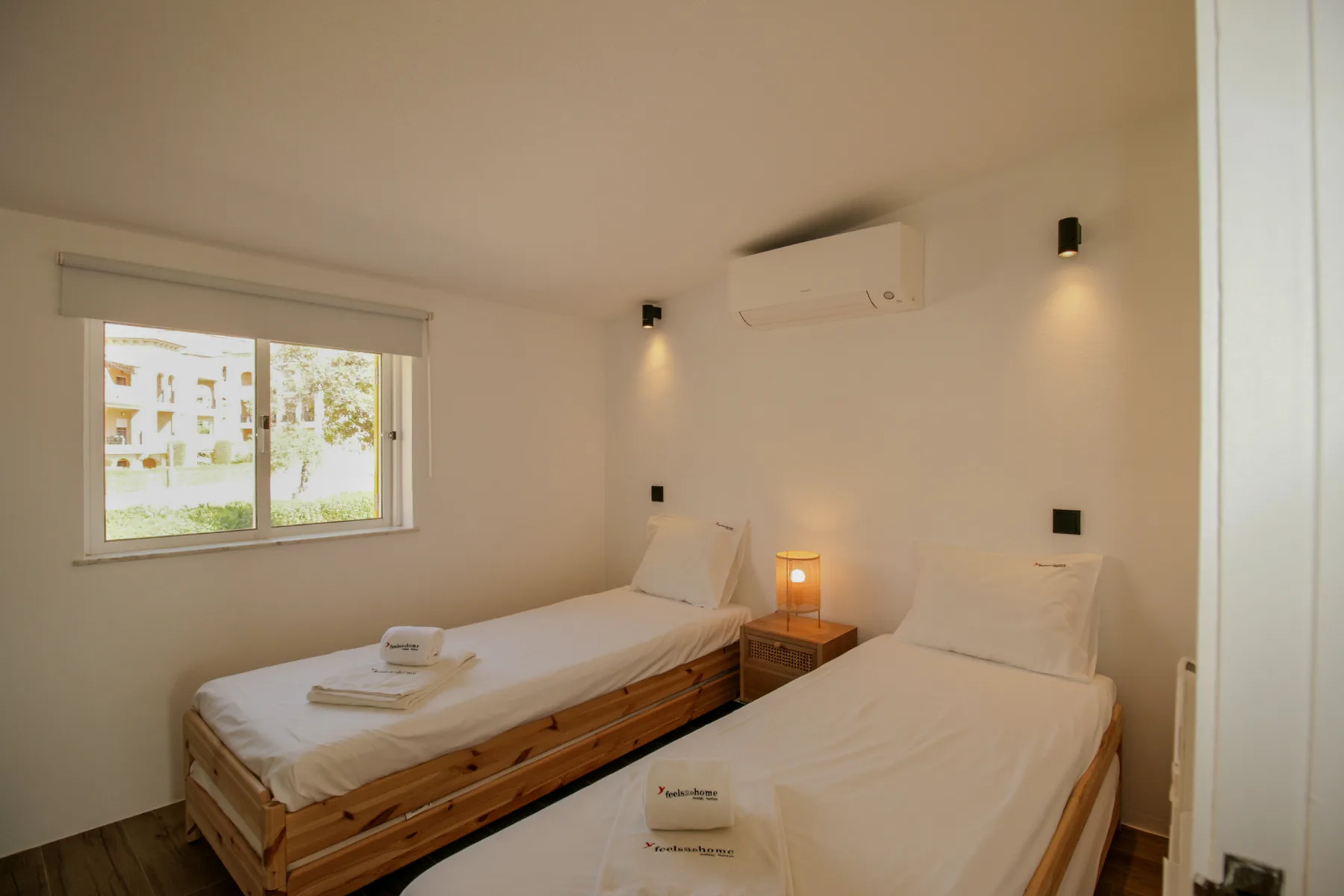 Un dormitorio con dos camas individuales, una mesita de noche y una ventana.