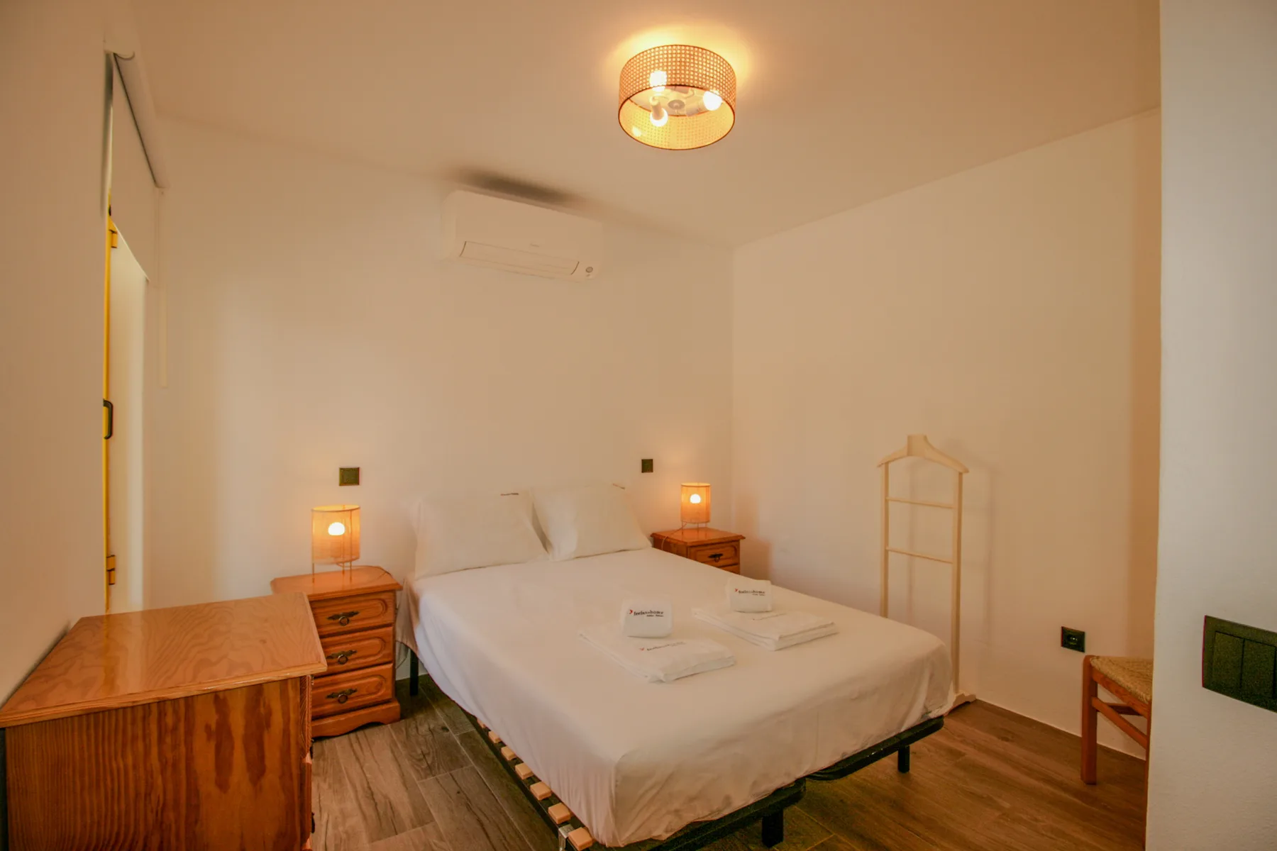Un dormitorio con cama doble, mesillas de noche e iluminación cálida.