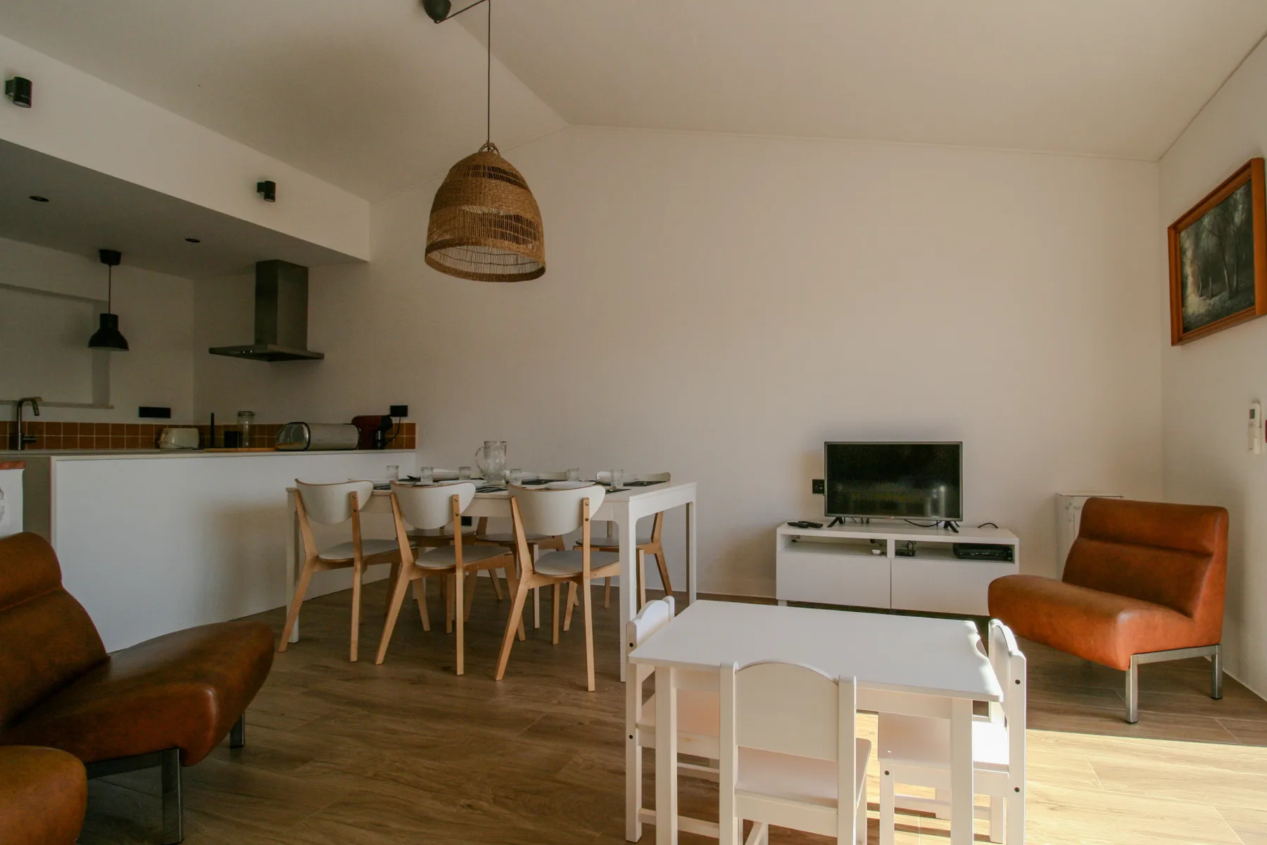 Una sala-comedor abierta con barra de cocina y televisor.