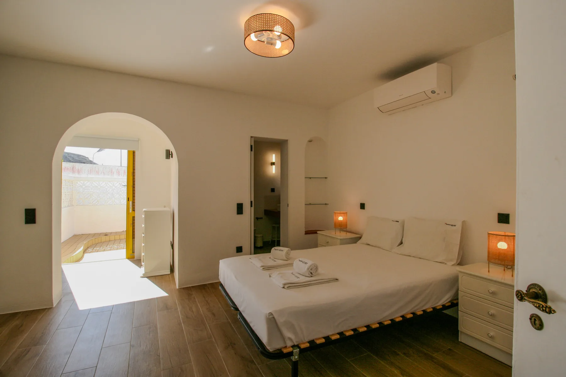 Un dormitorio con una cama doble, mesitas de noche y una entrada arqueada.