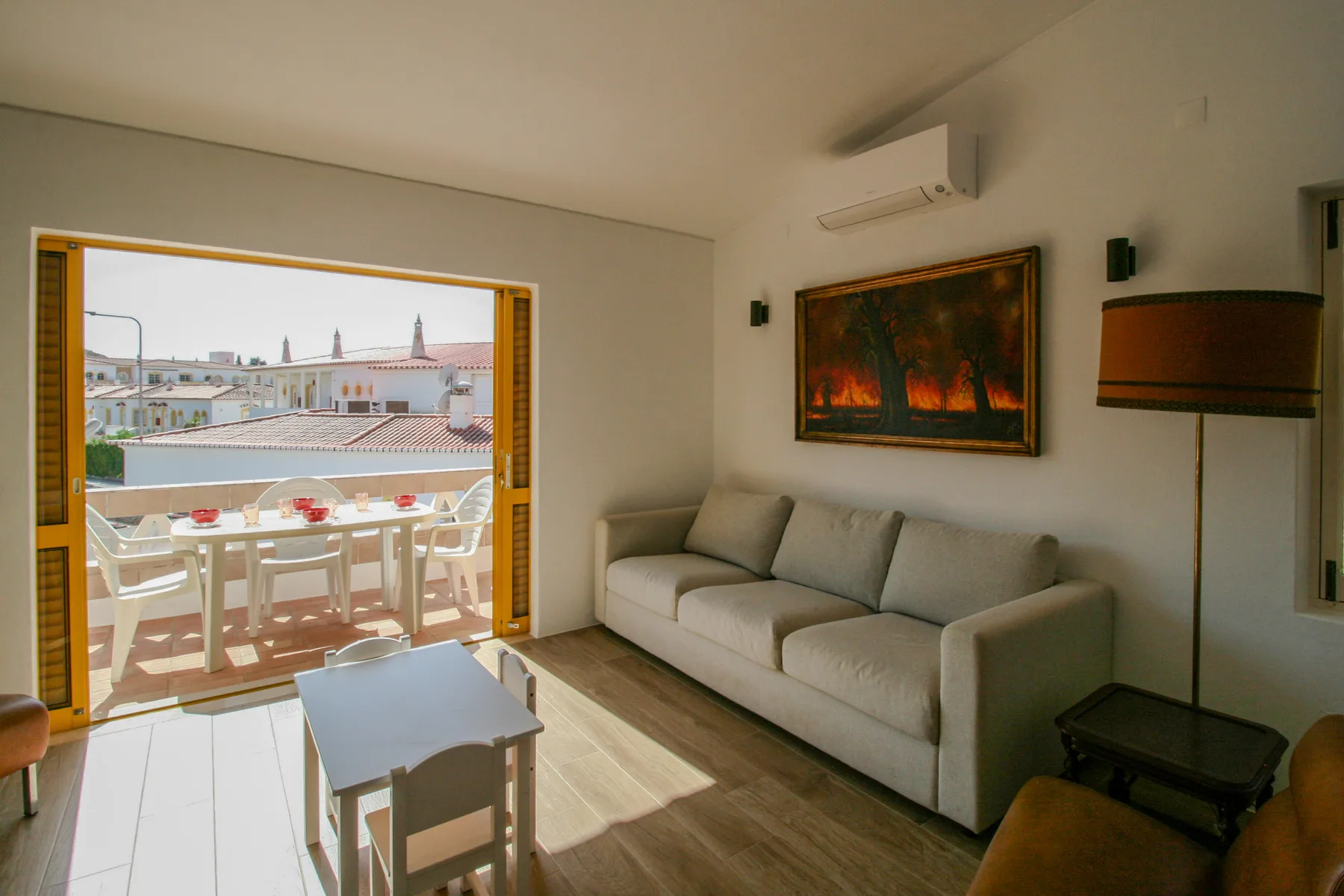 Una sala de estar con asientos y una mesa junto a un balcón abierto.