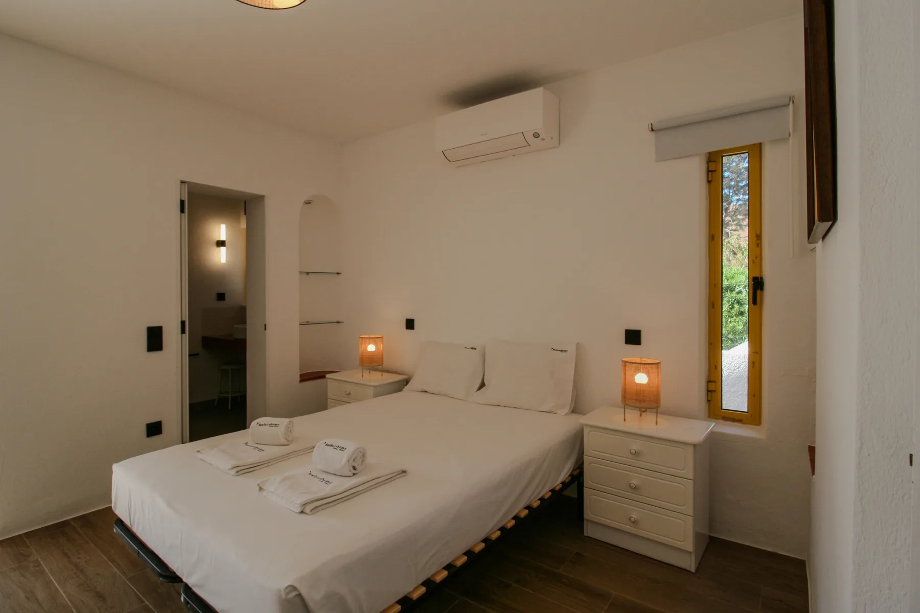 Un dormitorio con una cama bien hecha y dos lámparas de mesilla.