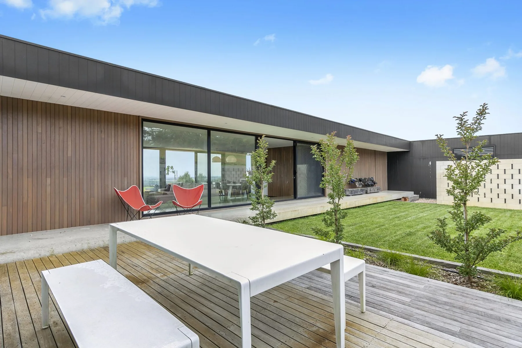 A modern house patio with outdoor seating beside a green lawn.