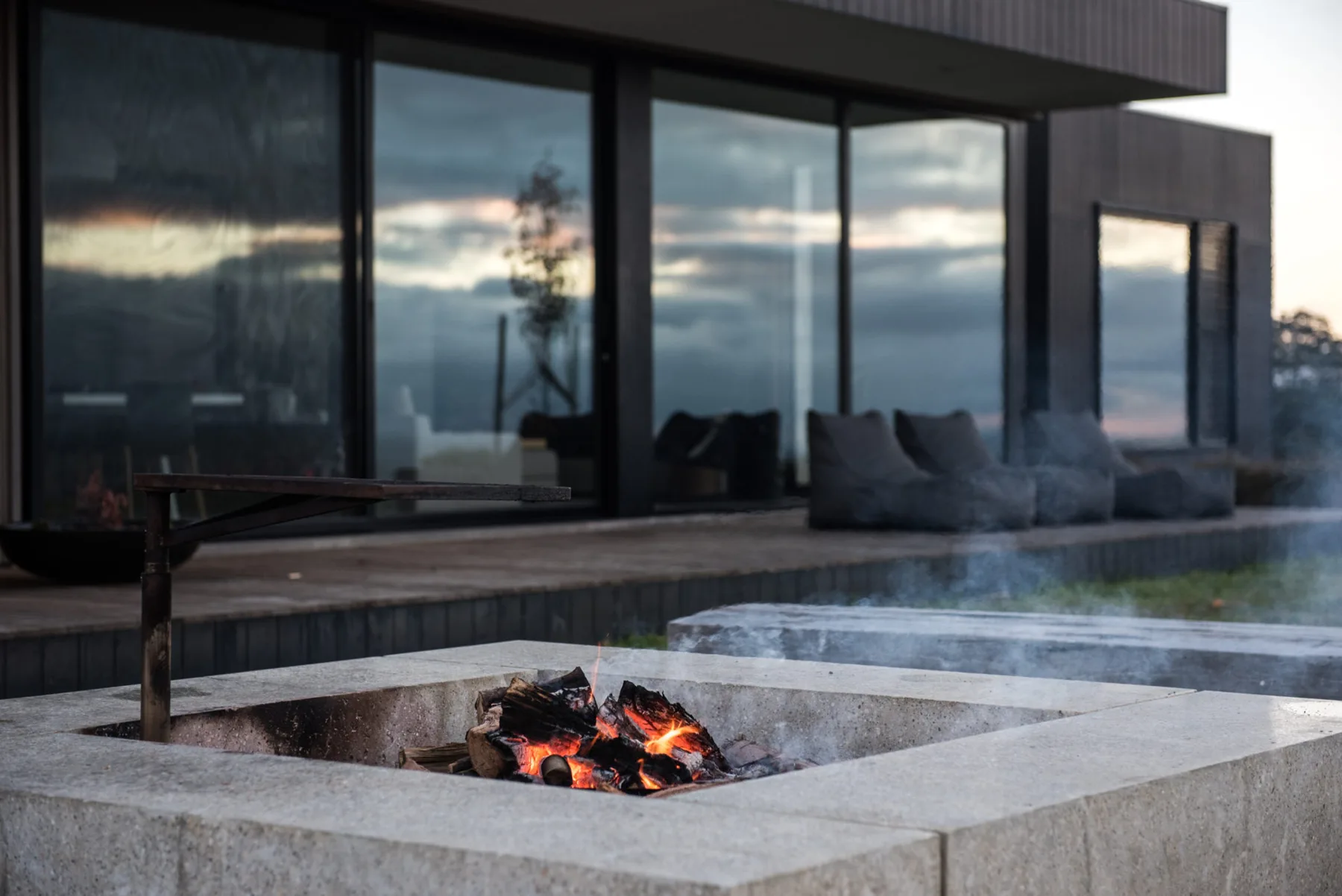 A modern patio with a rectangular fire pit in front of glass doors.