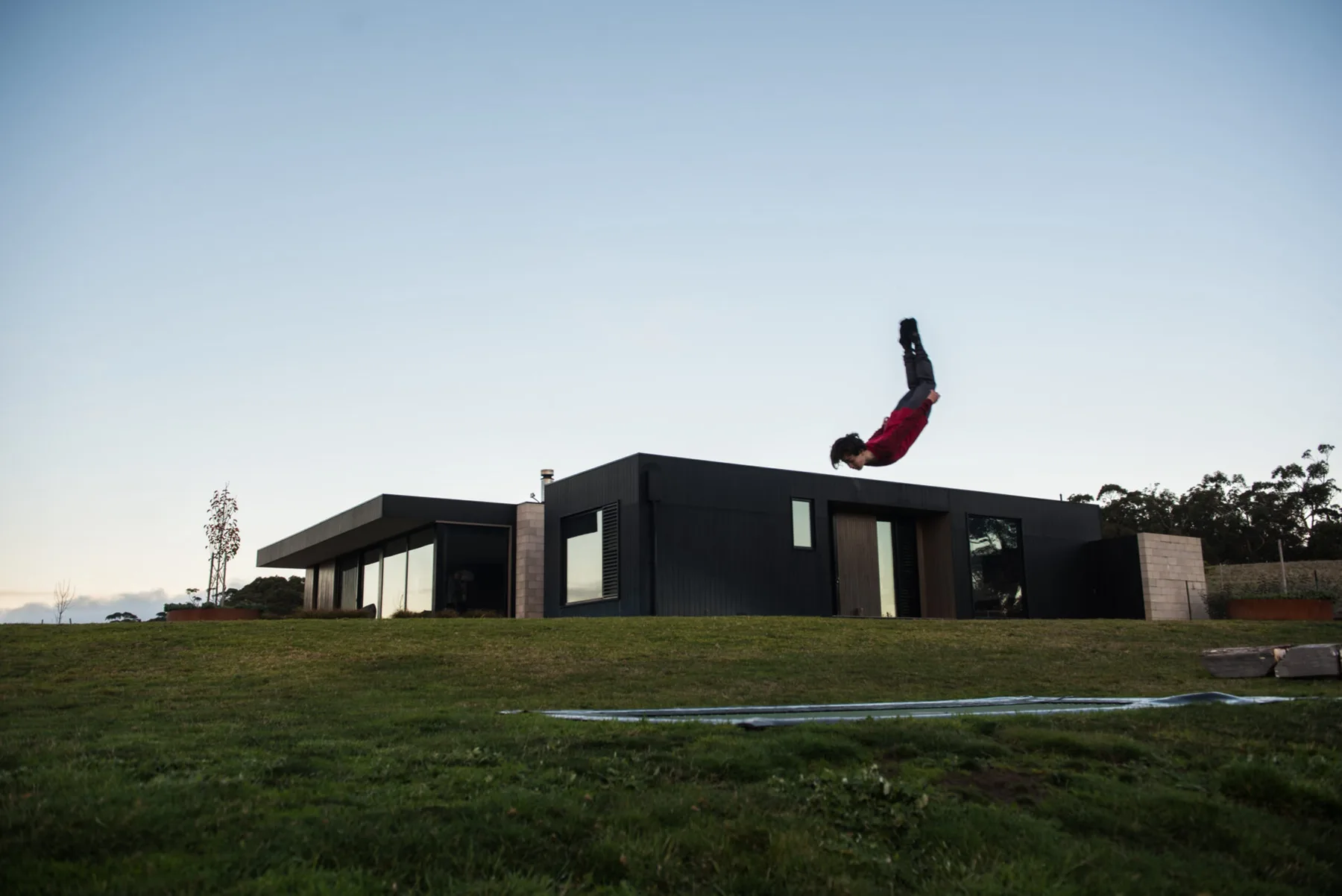 A modern house stands on a grassy lawn beneath a clear sky.