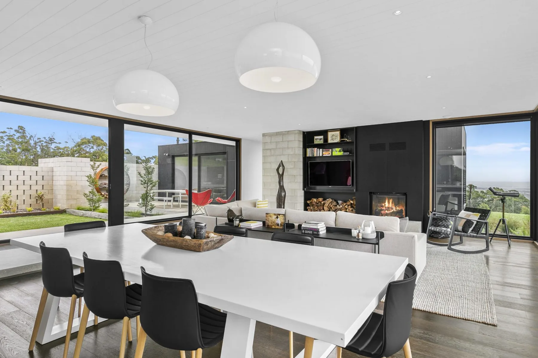 A modern living and dining area with large windows and seating.