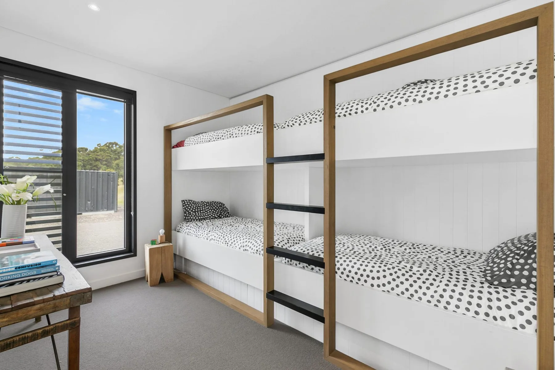A bright bedroom with bunk beds and a window overlooking greenery.