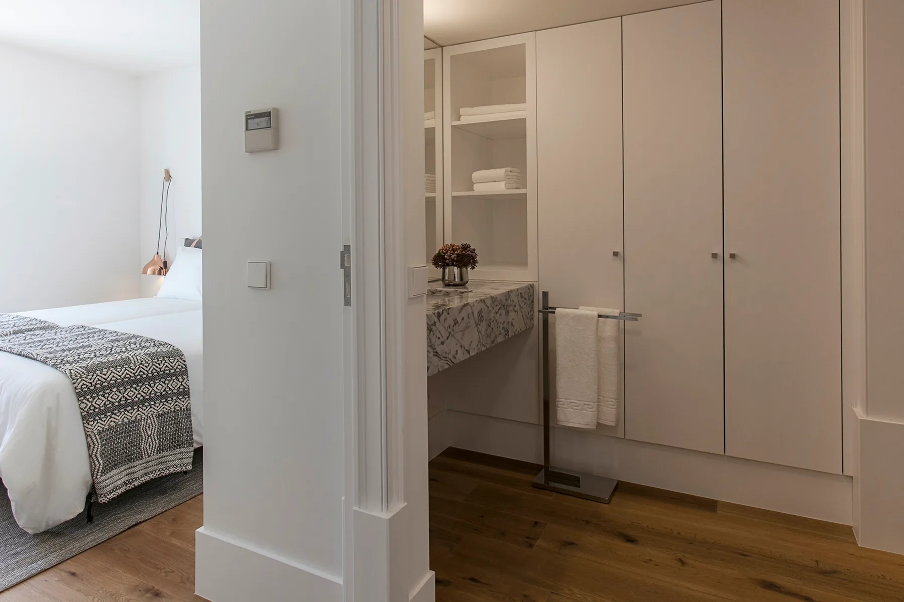 Bedroom and bathroom vanity area with built-in cabinets and wood flooring.